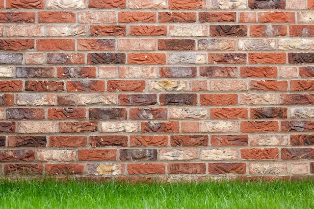 Un mur en brique rouge et de l'herbe